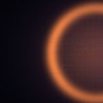 Glowing orange silicon wafer with a grid of chip dies on a dark background